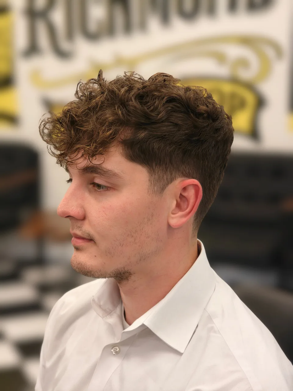 Curly hair with a textured fringe and a clean taper around the temple and ear