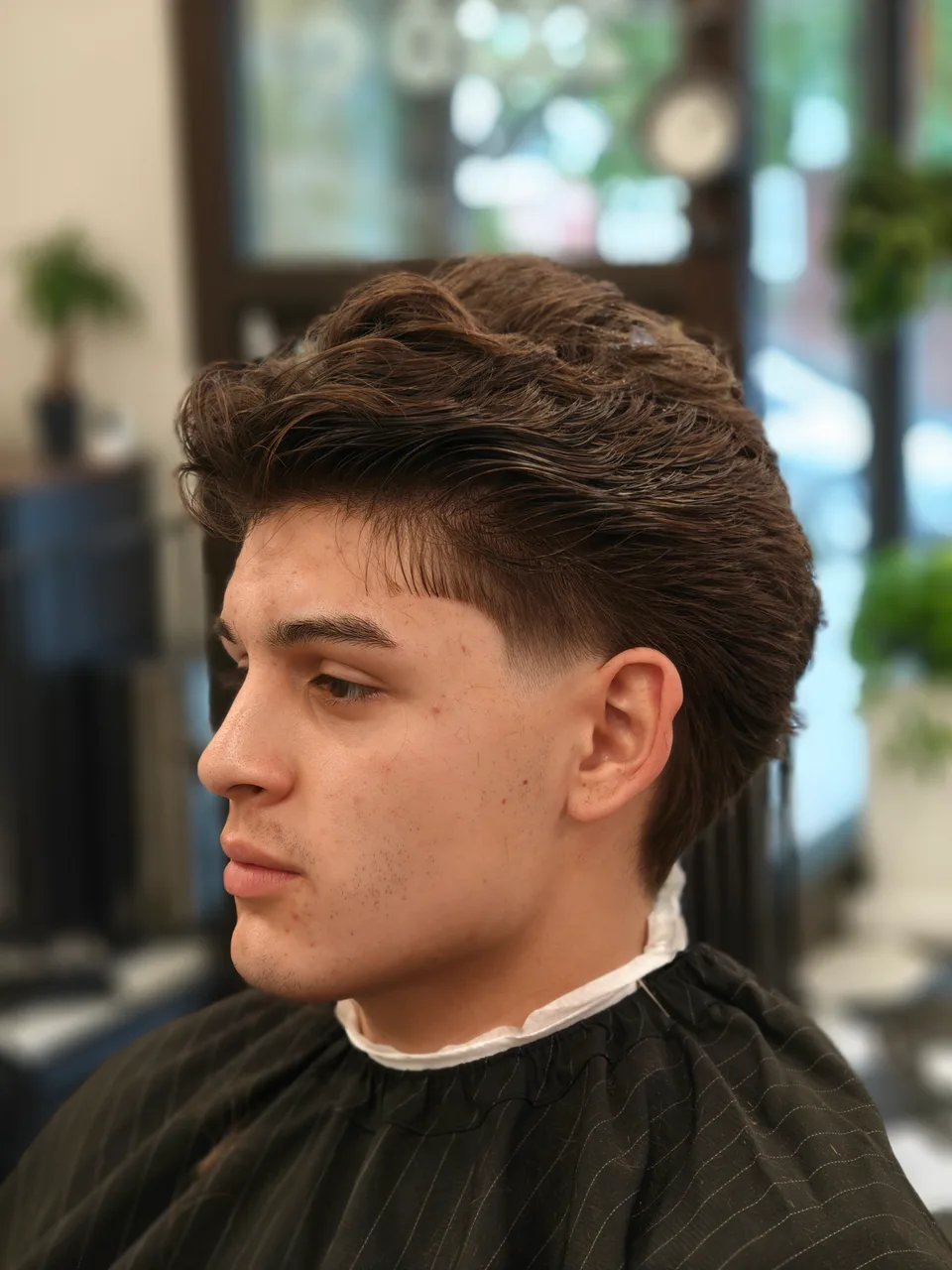 Swept-back brown hair with volume on top and a closely tapered temple, viewed from the side
